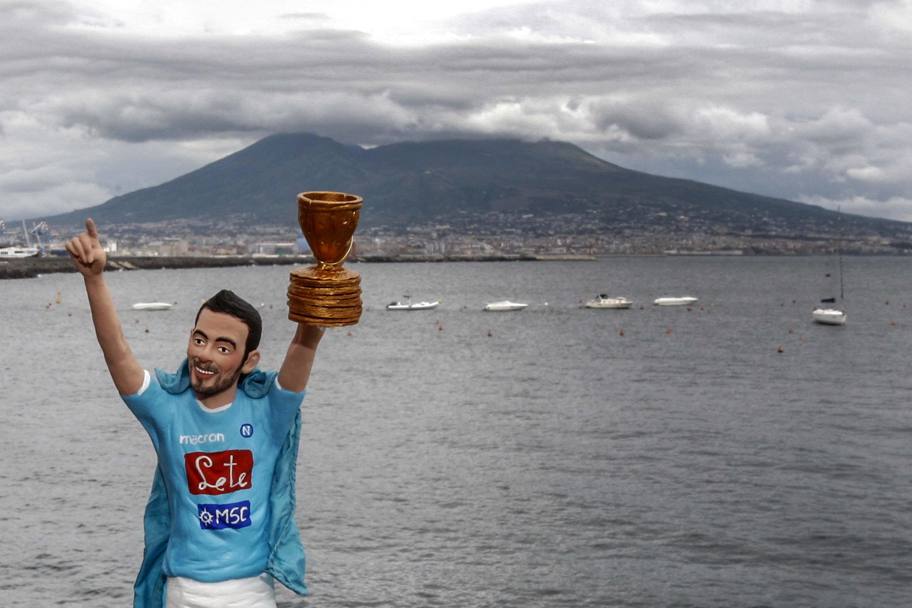Il golfo di Napoli fa da cornice alla creazione del maestro pastoraio di San Gregorio Armeno, Genny di Virgilio, che ha realizzato la statuina del calciatore Ezequiel Lavezzi, con indosso un mantello azzurro, mentre alza la Coppa Italia (Ansa)